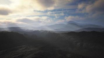 black volcanic dust and mountains with fog in background photo