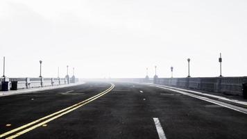 Asphalt highway and mountain in deep fog photo