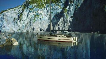 White yacht anchored in a bay with rocky cliffs photo