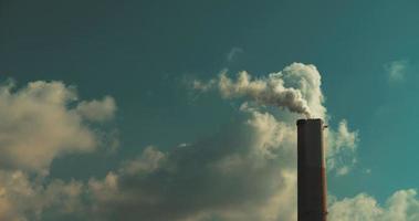 Smoke coming out of a coal power plant chimney against blue sky and clouds video