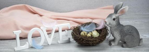 Word love, easter bunny, feathers and easter eggs. Wooden letters of the alphabet in the form of the words LOVE on a light background. Selective focus. photo