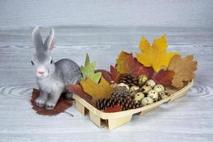 Easter Bunny and Easter eggs in a wicker basket. Spring composition on a light background. photo