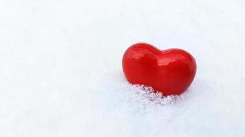 Heart in the snow. Declaration of love. A red heart is buried in white snowflakes. photo