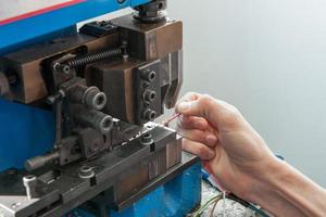 hands working behind the machine for assembling the cable with terminal connector photo