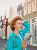 Portrait of redhead young woman in straw hat and with travel bag with paper map travel over West Europe. Travel and lifestyle photo