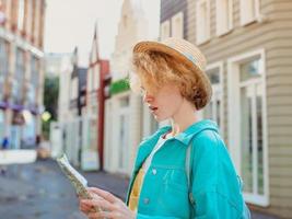 redhead young woman travel over West Europe and using paper map in unknown town. Travel photo. Lost in new city photo