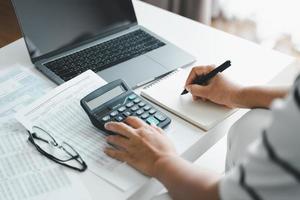 Woman is calculating annual tax, monthly expenses with calculator and filling form of Individual Income Tax Return. Season to pay Tax and Budget planning concept. photo