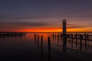 puesta de sol con nubes en el lago con pequeño faro foto