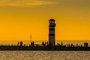 lighthouse and people at the lake while sunset photo