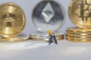 valueable crypto coins bitcoin ether and ada in a row with a single worker on gray background detail photo