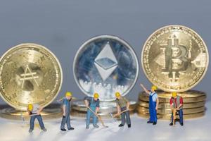 valueable crypto coins bitcoin ether and ad with many worker in a row on gray background close up photo