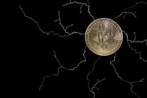 single valueable bitcoin from crypto currency with many lightnings on black photo