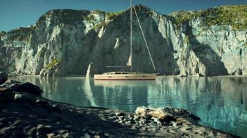 White yacht anchored in a bay with rocky cliffs photo