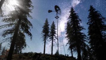 retro windmill in mountain forest with stars. hyperlapse photo