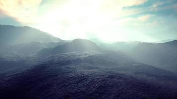 black volcanic dust and mountains with fog in background photo