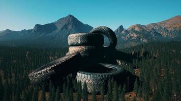 concept of environmental pollution with big old tires in mountain forest photo