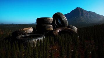 concept of environmental pollution with big old tires in mountain forest photo