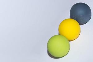 tres bolas de diferentes colores para masaje en una fila en diagonal de fondo gris foto