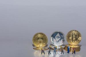 valueable crypto coins bitcoin ether and ad with many worker in a row on gray photo
