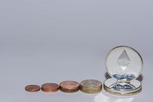 euro coins and ether coins from crypto currency stacked in a row with gray background view photo