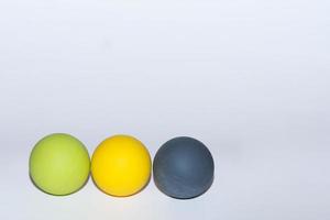 three different colored balls for massage in a row on gray background left photo