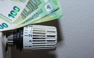 aumento de los precios de la energía y regulador termostático del consumo de energía de la calefacción con billetes de 100 euros foto