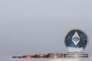 euro coins and silver ether coins from crypto currency stacked in a row with gray background flat photo