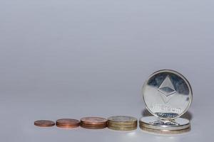 euro coins and ether coins from crypto currency stacked in a row with gray photo