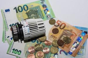 aumento de los precios de la energía y regulador termostático del consumo de energía de la calefacción con diferentes billetes y monedas de euro detalle foto