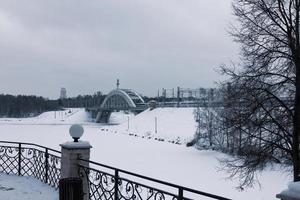 View of a frozen river and a railway bridge in a snowy winter. photo