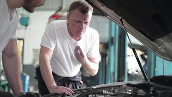 monteur technicus teampersoon repareert automotor, motor-autoservice en professionele controle van onderhoud in garage, autovoertuig of auto-machinebezetting video