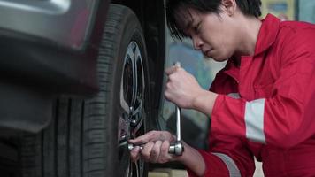 service d'atelier de technicien, mécanicien changer le pneu et la roue de voiture dans le garage automobile, outil d'entretien et de réparation automobile pour le transport de véhicules, occupation de l'homme avec pneu au travail video