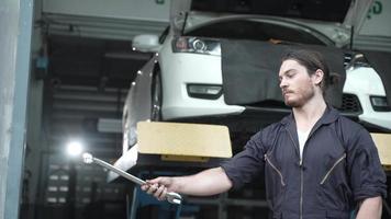 técnico mecânico mostrando uma chave no serviço de garagem de automóveis de loja, manutenção de transporte de veículos e ferramenta de reparo de automóveis, ocupação de pessoa de homem em ação em câmera lenta video