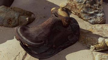 very old horse saddle on sand beach photo