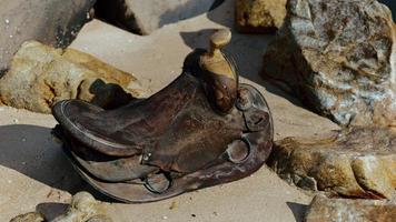 very old horse saddle on sand beach photo