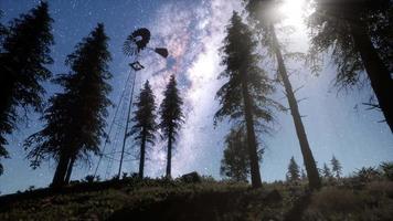 moinho de vento retrô na floresta de montanha com estrelas. hiperlapso video