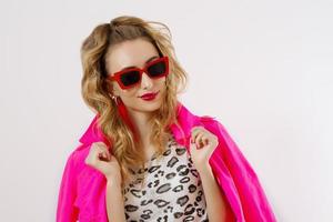 Happy, shock, excited woman face closeup. Girl in bright pink autumn clothes, red sunglasses isolated on white background, copy space. Beautiful female surprised, cheerful. Fun funny model screaming photo