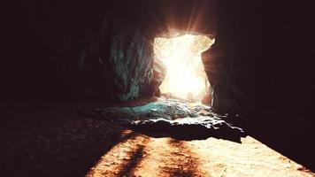 big dark cave and sun light from jungle forest photo