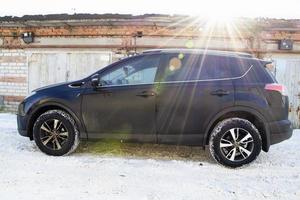 Toyota Raw4 against the background of brick garage and rusty metal doors on a sunny winter morning. photo