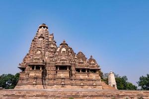 hermosa arquitectura de templo indio antiguo situada en khajraho, con hermosas tallas en una roca por esculturas antiguas foto