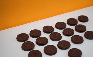 Chocolate cookies kept in a pattern on a white paper with a yellow background photo