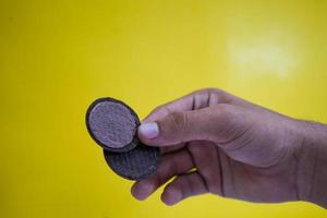 hands holding chocolate biscuits on a yellow background with copy space photo