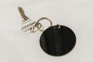 Hotel room key with round black blank pendant white background. photo