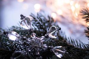 juguetes de navidad, copos de nieve de cristal en la rama de un árbol de navidad. fondo bokeh con guirnalda foto