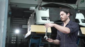 mechanikertechniker, der einen schraubenschlüssel im autowerkstattservice, fahrzeugtransportwartung und autoreparaturwerkzeug, personenbesetzung in zeitlupenaktion zeigt video