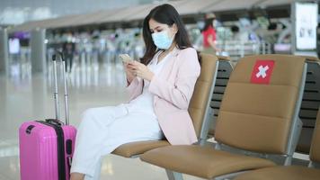uma mulher viajante está usando máscara protetora no aeroporto internacional, viaja sob pandemia covid-19, viagens de segurança, protocolo de distanciamento social, novo conceito de viagem normal. video
