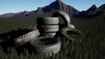 concept of environmental pollution with big old tires in mountain forest video