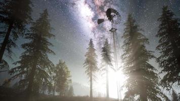 moulin à vent rétro dans la forêt de montagne avec des étoiles. hyperlapse video