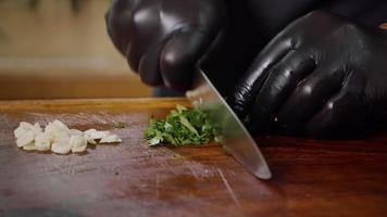 cortar perejil verde fresco en una tabla de cortar de madera. industria de alimentos. video