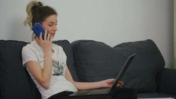 Woman sitting on couch in living room and discussing with colleagues via phone call video